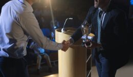 Businessman appreciating business male executive on stage in aud